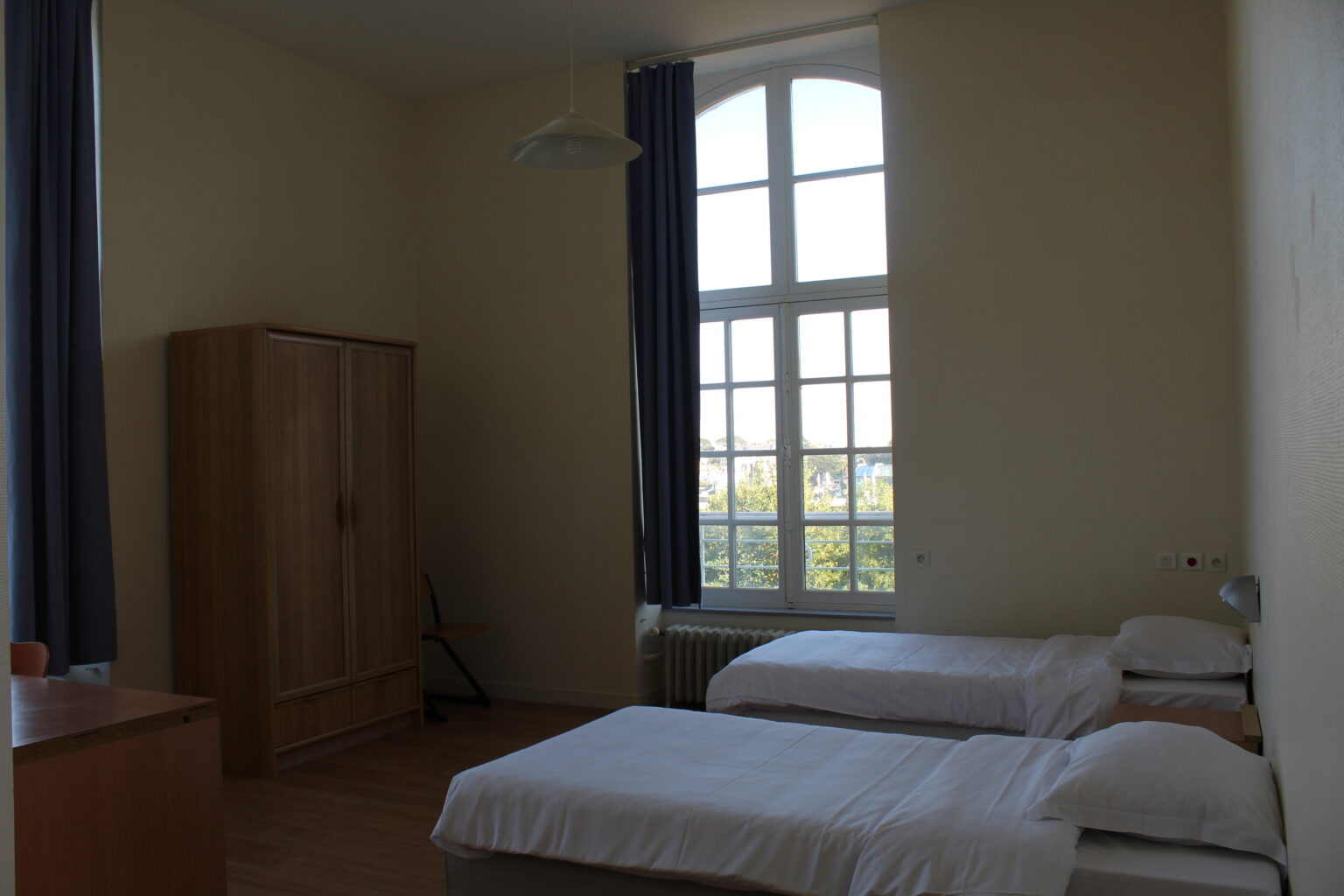 Chambre double avec deux lits et une grande fenêtre